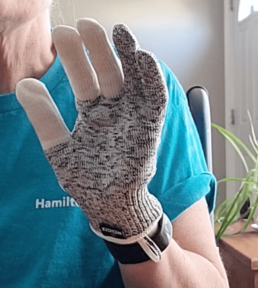 A person holding up their left hand with the glove on