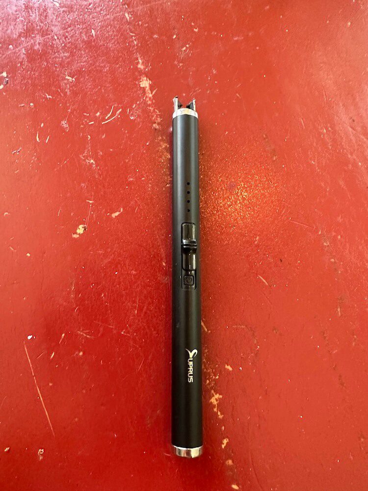 Top view of the button pushed forward and the lighter prongs extended on one end. The activation button is visible but also black and small and hard to see.