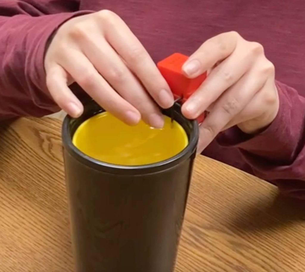 A person's hands using the red and black indicator on a glass of water