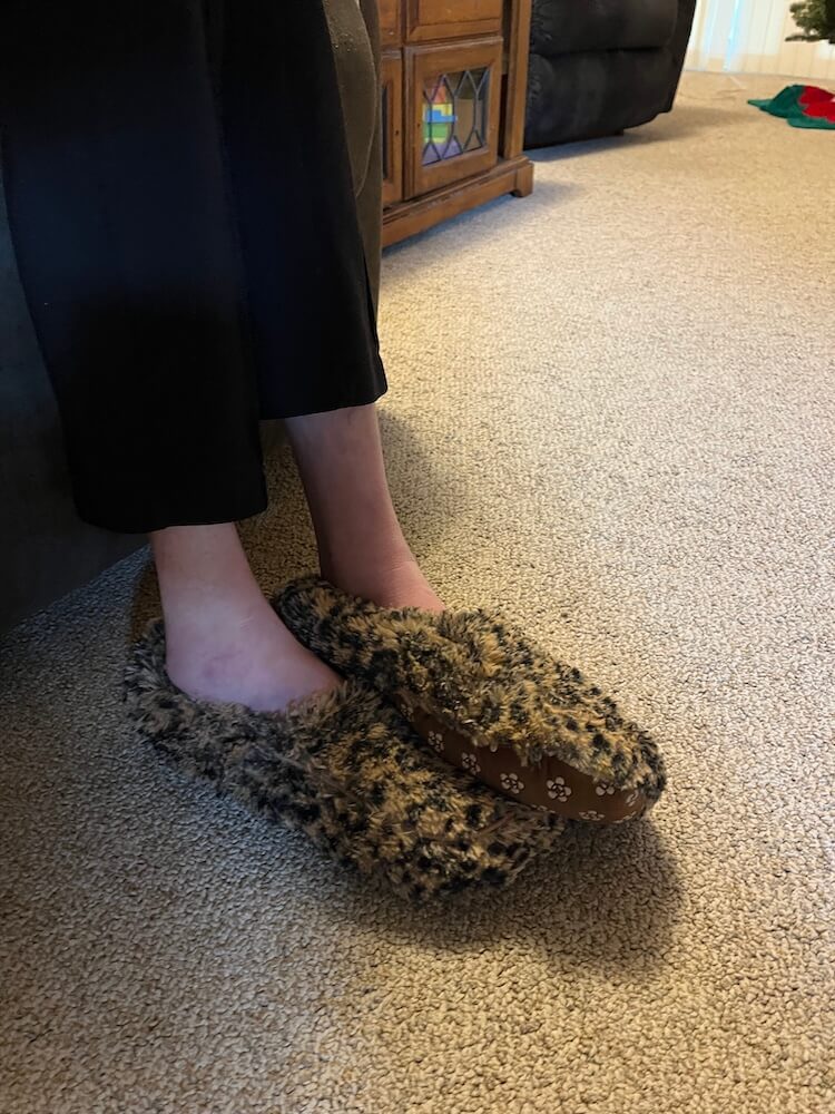 Side angle of shaggy leopard slippers on someone's feet