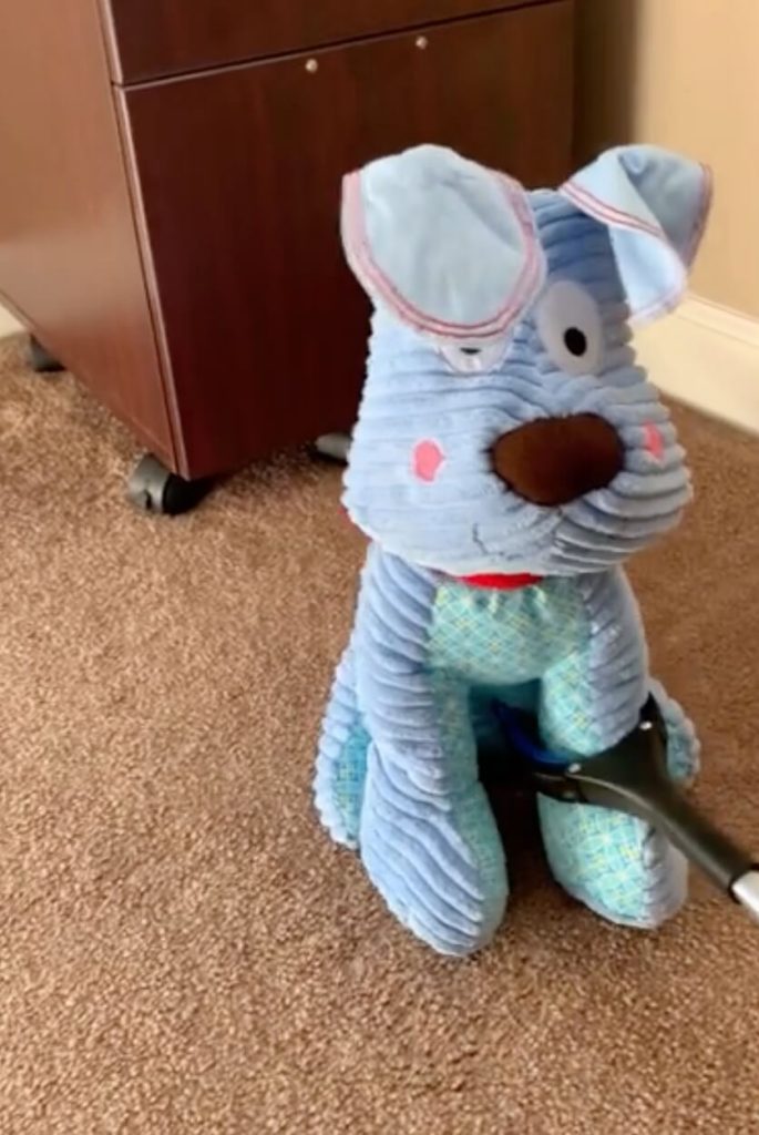 Grabber is closed around the leg of a blue, dog stuffed animal.