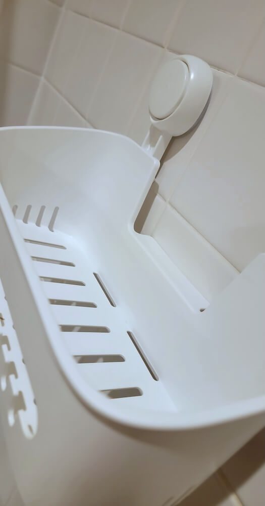 Top-down view into the white shower caddy, which has openings for the water to run through.