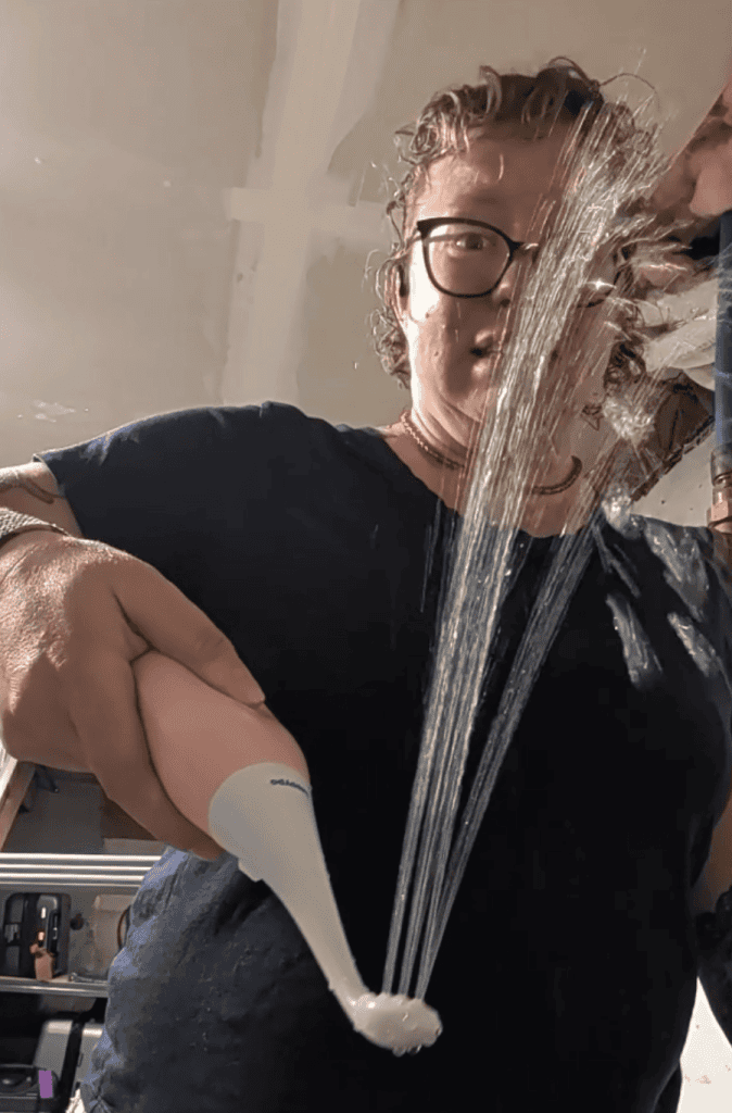 A person demonstrating a hand held bidet device squirting water upwards.