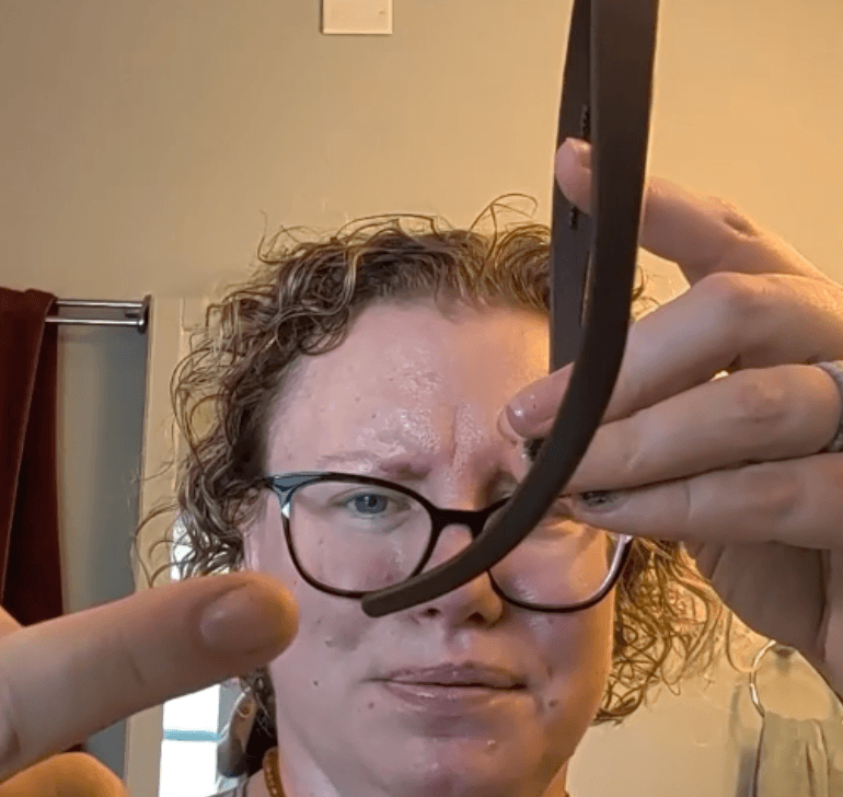 A person pointing to the curved end of a black plastic headband.